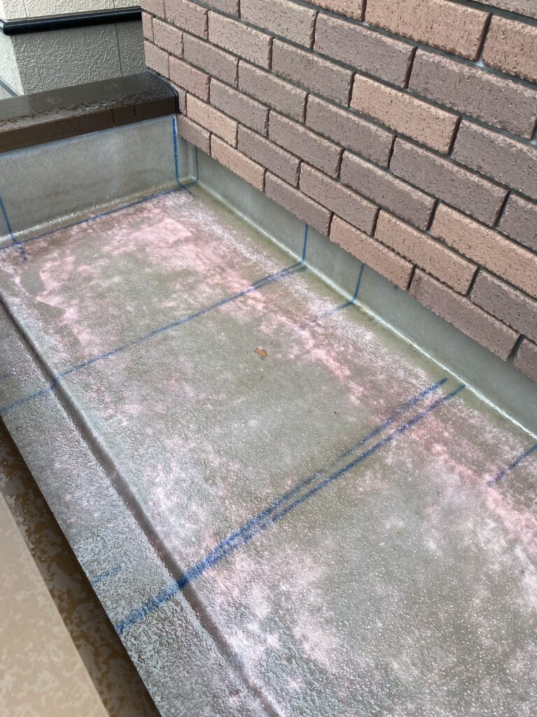 雨に打たれてピンク色に変色し硬化不良を起こしたFRP防水層