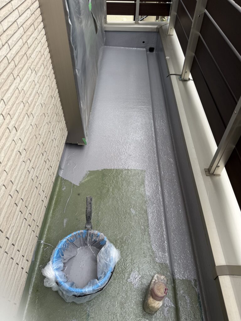 一戸建てのベランダでFRP防水層へトップコートを塗装する作業